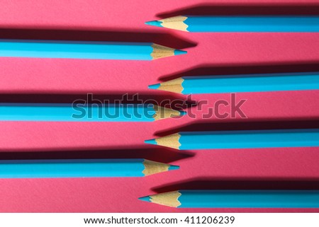 many blue pencils are closeup on pink background