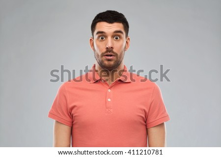 emotion, advertisement and people concept - surprised man in polo t-shirt over gray background Royalty-Free Stock Photo #411210781