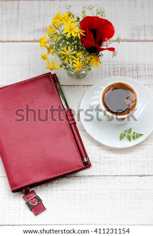 A cup of coffee and a bouquet of flowers, a notebook
