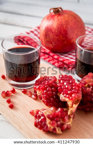 glass of pomegranate juice with fresh fruits on wooden table