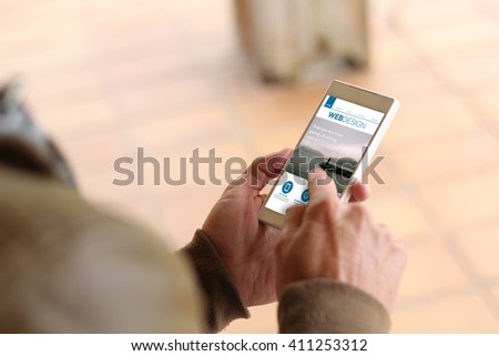 man touching the screen of his smartphone at street showing web design website. All screen graphics are made up.