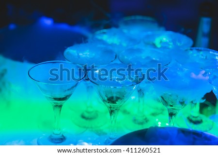 Beautiful pyramid line of multicolored different colored alcohol cocktails with mint on a tropical style party, martini, vodka,and others on decorated catering bouquet table on open air event