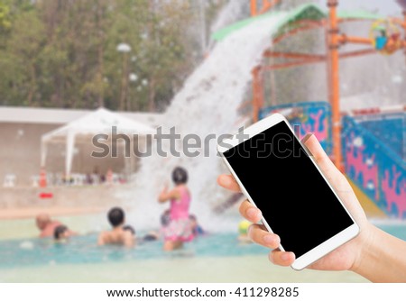 woman use mobile phone and blurred image of people in water park