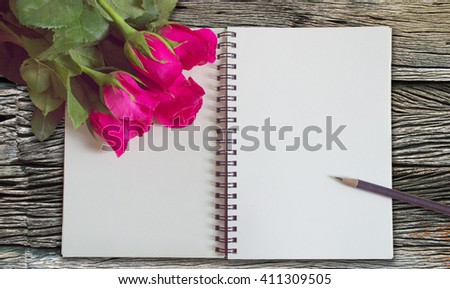 Vintage,retro of note book paper and pencil with rose on wooden background soft focus.