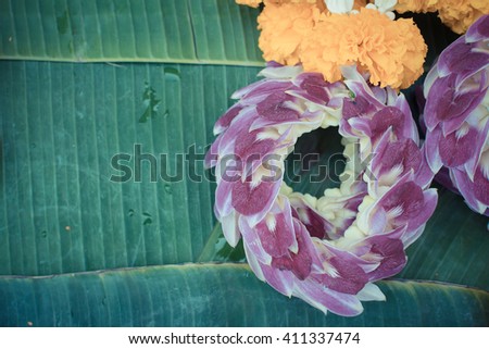 Beautiful garland jasmine and orchids and calendula flower on green banana leaf , process in vintage style