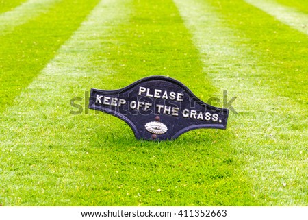 A beautiful green garden lawn that has just been mowed with an attractive pattern of stripes and a sign of Please Keep Off The Grass