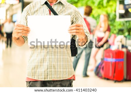 Man hands holding empty signboard at international airport meeting point - Young casual guy with blank sign for advertising text is receiving travelers at arrival  gate -  Main focus on male hands