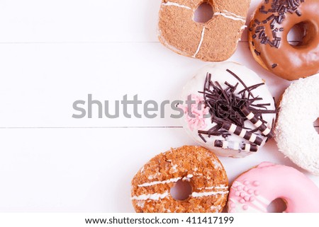 Colored delicious donuts with chocolate, coconut and crispy sprinkles on a wooden background. Top view with copy space