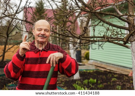 elderly man with a garden tool gives tips and tricks for working