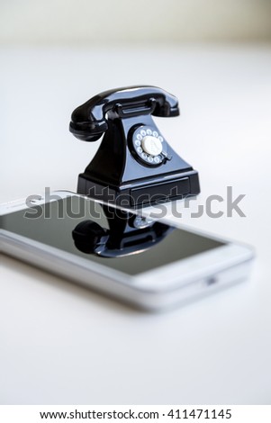 Modern white smartphone and toy retro telephone standing together on a white background as a symbol of technological evolution