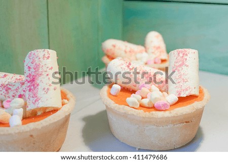 Closed up of Homemade mini tarts with meringue and marshmallow on top, selective focus on marshmallow on vintage wood background