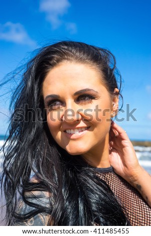 Heavily tattooed plus sized female model on South Shields beach.  She is smiling, looking happy.