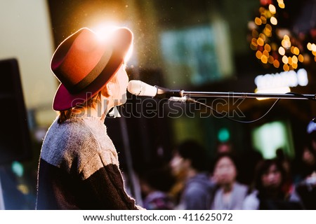 Female singer, performing her vocal sound. With lens flare and spotlight. Royalty-Free Stock Photo #411625072