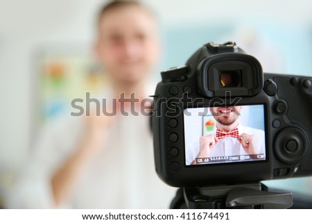 Young male blogger with tie bow on camera screen