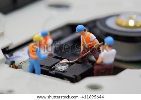 Selective focus of miniature engineer and worker fixed to clean CD rom reader of mainboard computer and use for business background.