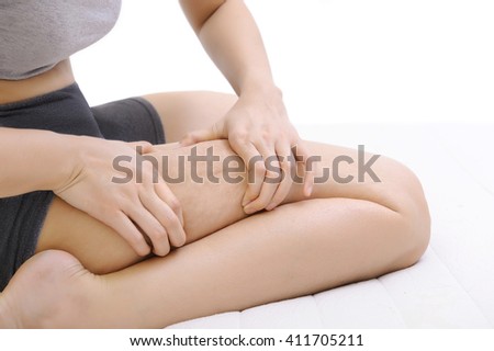 woman holding and pinching cellulite on her leg on white background