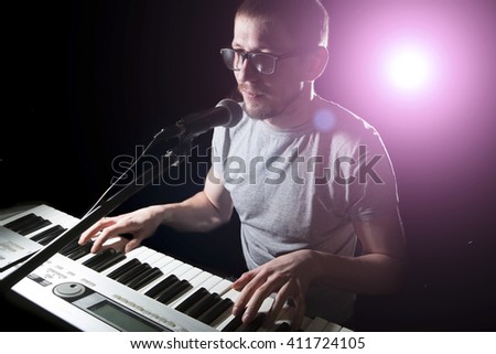 keyboarder is playing and singing on dark background