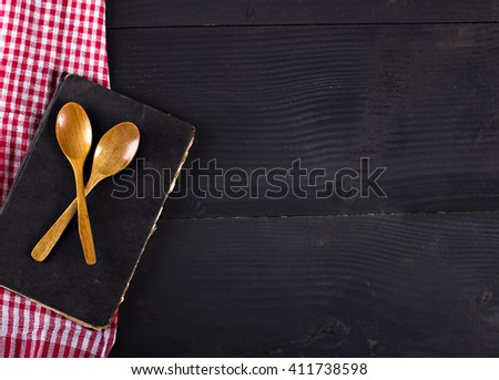 
napkin, a recipe book and wooden spoon on a black background