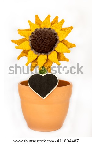 a crocheted sunflower in a flowerpot and a heart table