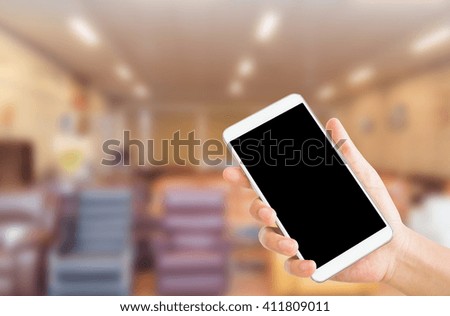 woman use mobile phone and blurred image of furniture shop in the mall