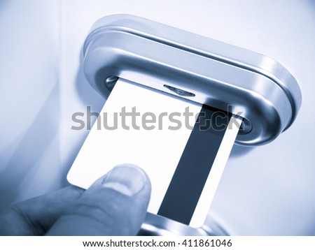 Person's hand inserting a magnetic stripe keycard into a hotel room electronic keycard door lock