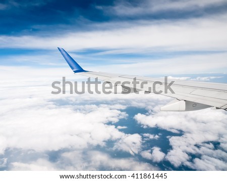 Airplane wing above the clouds with a blue sky