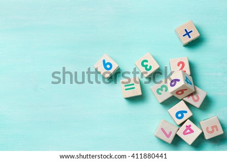 Wooden cubes with numbers on a turquoise wooden background. 