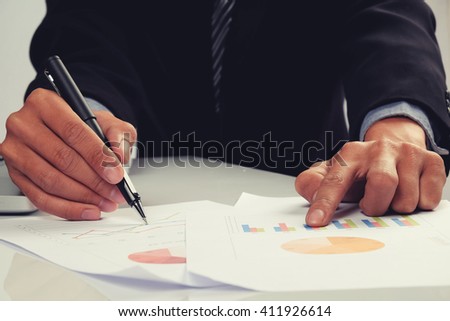 business man documents on office table with laptop computer and graph business discussing data in the background.Vintage tone
