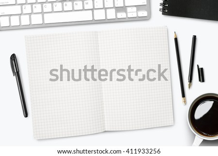 White desk with grid lined notebook and other supplies. Top view with copy space.