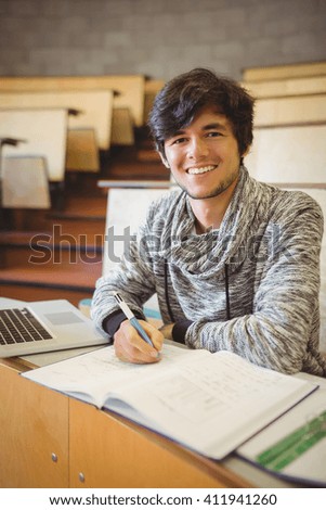 Portrait of young student sitting at desk reading notes in the classroom