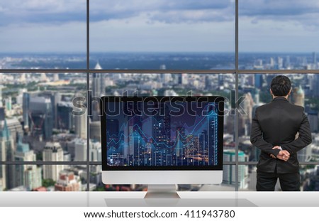 Back side of Businessman looking at city out off windows glass with Computer show Trading graph on the cityscape and world map background on the table in meeting room,Business financial concept