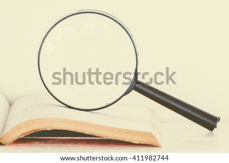 Magnifying glass and books on wooden table