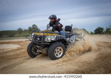 The race in difficult conditions on the sand on a quad bike. Royalty-Free Stock Photo #411992260