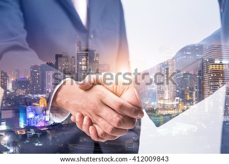 Double exposure of business handshake for successful of investment deal and city night background, teamwork and partnership concept. 