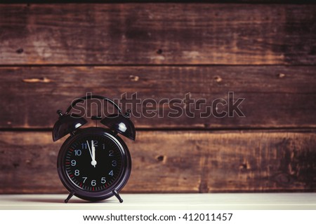 photo of the black clock on the brown wooden background