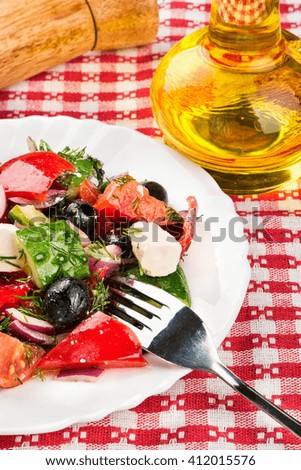 Plate of fresh Greek salad with oil bottle on a towel