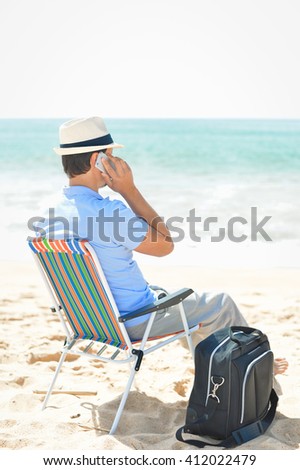 Man chilling on the beach talking on smartphone. Back side view of guy enjoying outdoors background