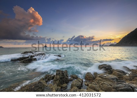 Stunning vibrant sunset over natural rock with strong water wave and sunset background at Selong Belanak Beach, Lombok, Indonesia. Image contain grain, noise and soft focus.