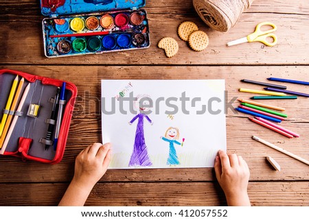 Unrecognizable girl drawing picture of her and her mother