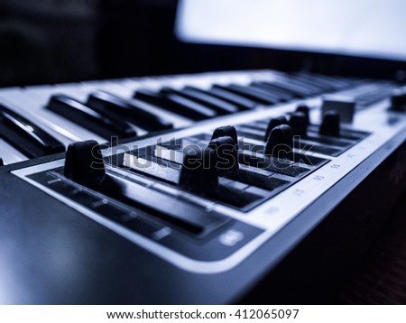 Macro view of black professional digital musical piano synthesizer with sliders. Background image of recording studio equipment. DJ using electronical device for making music.