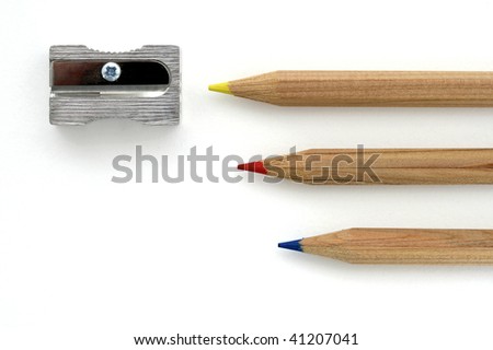 Three wooden color pencils with sharpener on white background