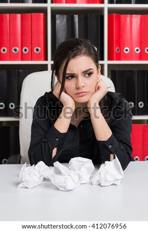 Annoyed business woman squeezed all the documents and scattered them on the table and looking to the side, in the background bookcase with folders for papers