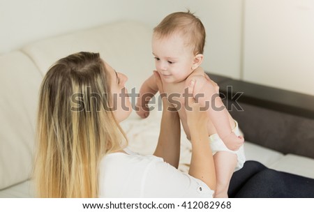Toned portrait of happy mother holding baby on hands