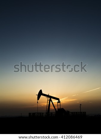 Sunset and silhouette of crude oil pump in the oil field  