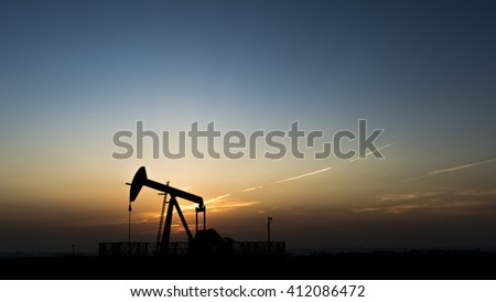 Sunset and silhouette of crude oil pump in the oil field  