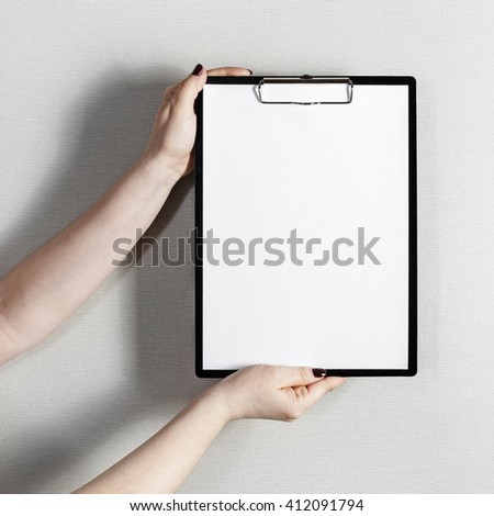 Blank paper poster in female hands. Clipboard with a blank paper. Mock-up for graphic designers portfolios.
