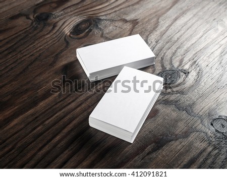 Photo of blank white business cards on a dark wooden background. Mock-up for ID. Blank template for graphic designers portfolios.