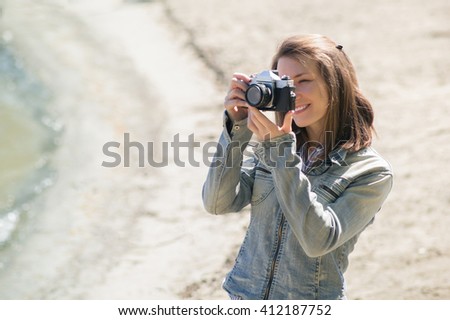 Young female photographer using old vintage camera outdoors