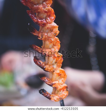 Vibrant picture of delicious grilled shrimp prawn spit on grill with flames in background, Grilled shrimps on the flaming grill on a banquet event, catering table
