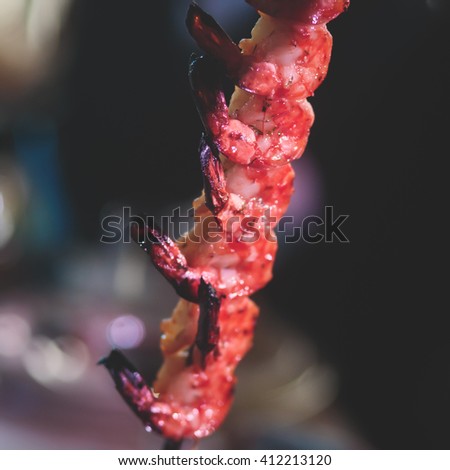 Vibrant picture of delicious grilled shrimp prawn spit on grill with flames in background, Grilled shrimps on the flaming grill on a banquet event, catering table